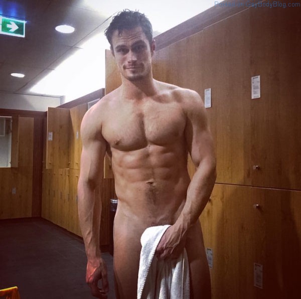 naked and handsome Mr. Martignago posing for a photo in a gym locker room while holding a while towel in front of his cock.