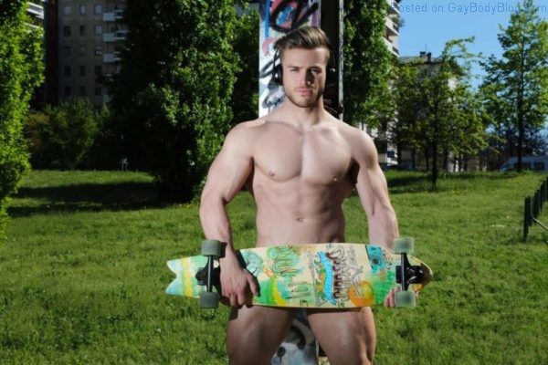 muscle jock standing outside with nothing but a skateboard