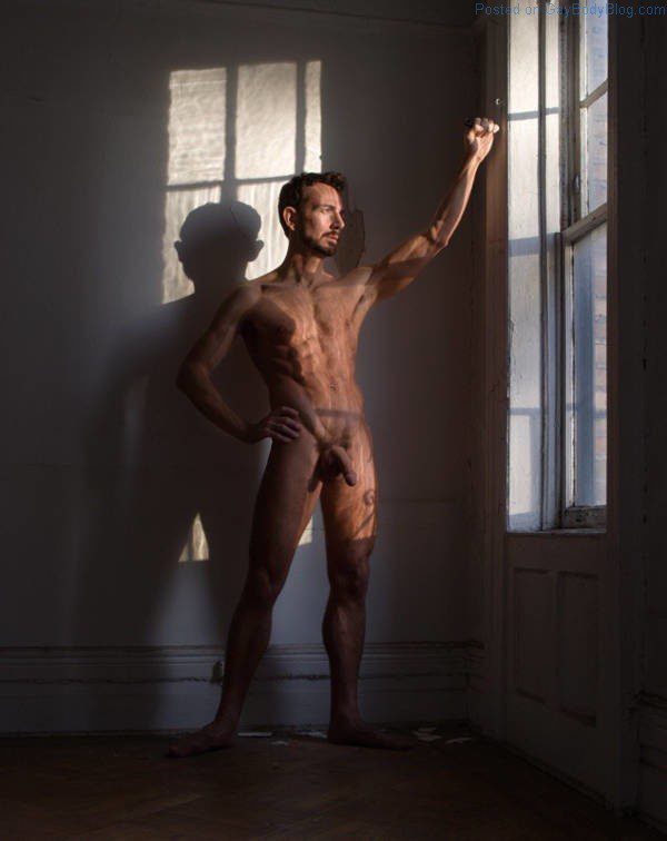 hung naked man standing in the light from a window