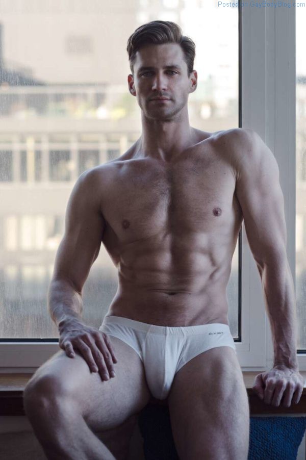 Male model Nicholas Cunningham sitting wearing just white underwear showing a prominent bulge