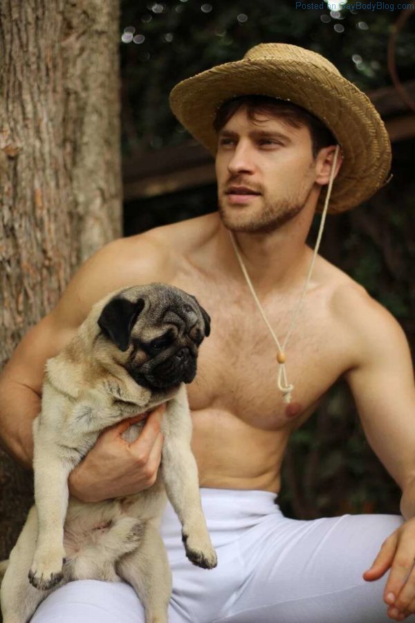 Sexy Male model Vinicius Piccoli holding a pug dog