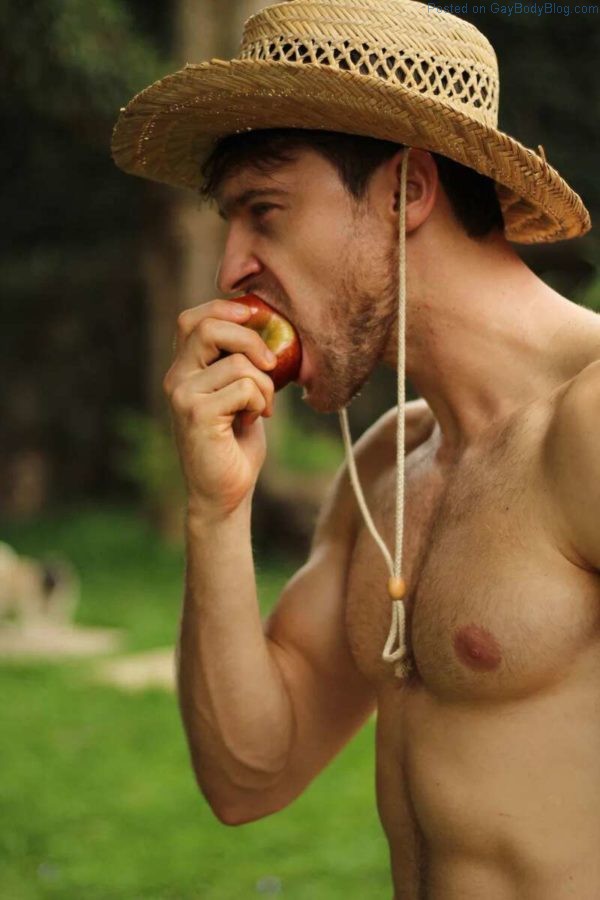 Shirtless and handsome Male model Vinicius Piccoli eating an apple