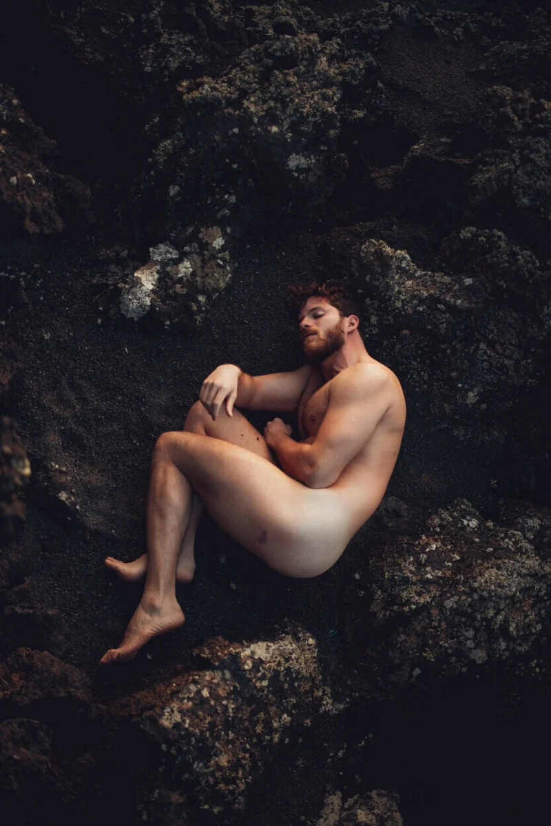 model Emanuele Mariotti nude among a rocky landscape