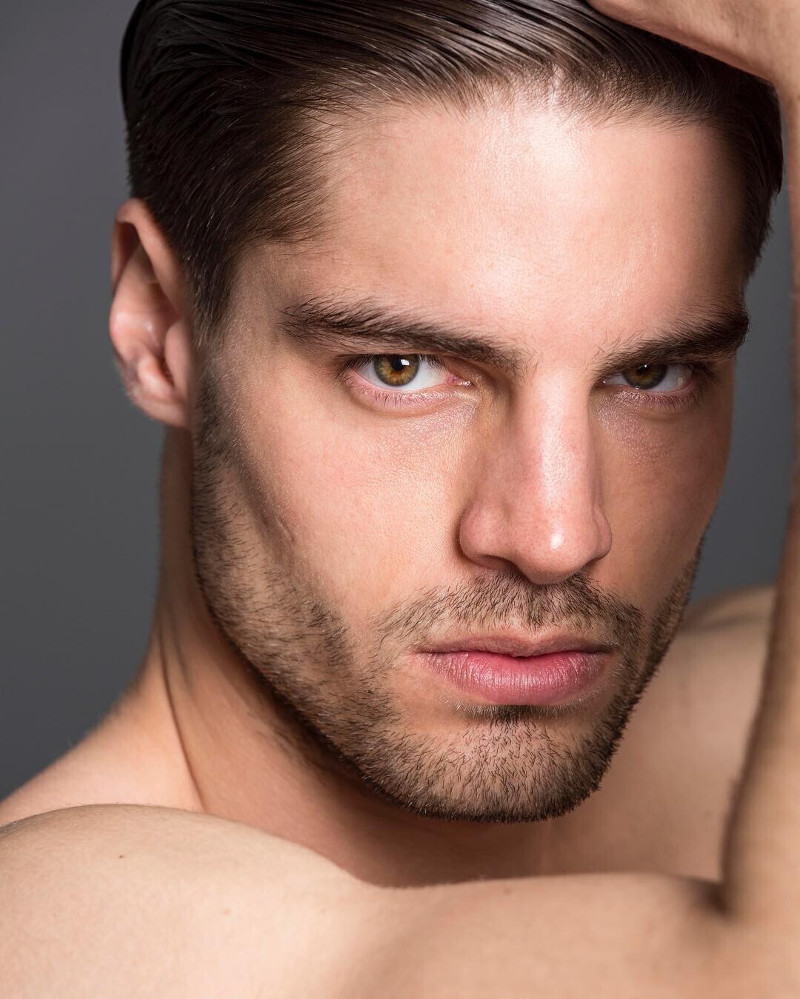 handsome male model with hazel eyes staring sternly into the camera in a close up portrait image