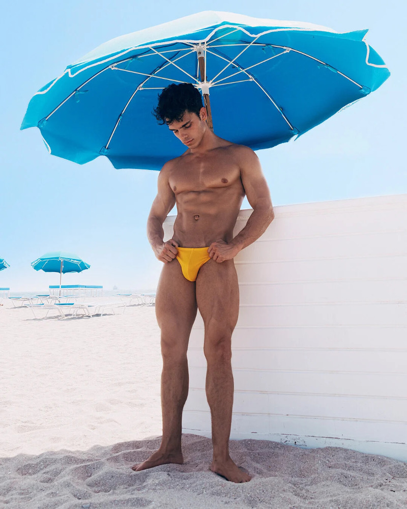 fit jock model Nik Ball at the beach showing off this bulging swimming trunks.